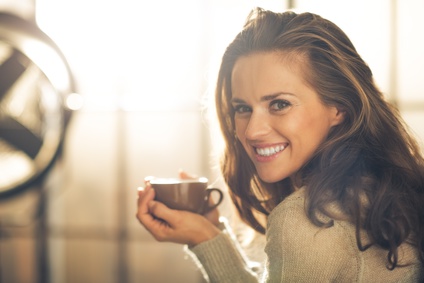Schönheit zeigt ihr tolles Lächeln und trinkt dabei Kafee