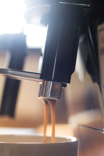 Kaffee läuft aus Kaffeeauslauf in eine Tasse.